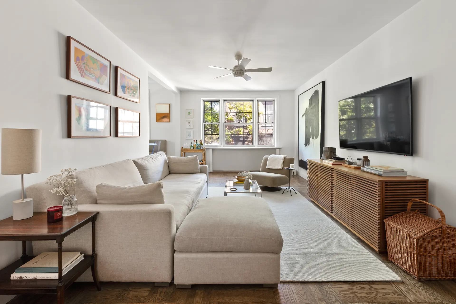 Sunlit living room with a linen sectional, gallery wall, and wood console