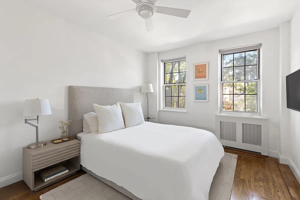 Bedroom with an upholstered bed and framed art between two windows