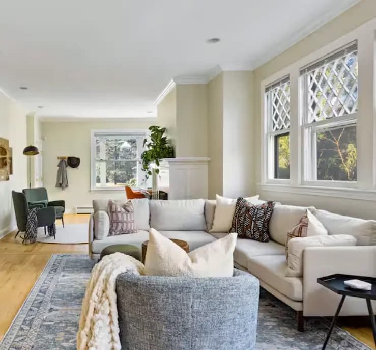 Living room with a sectional, patterned rug, and green accent chairs